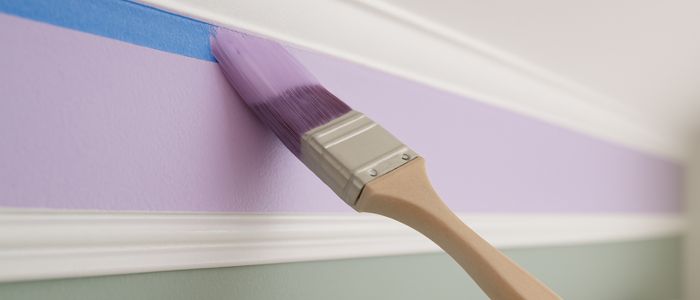 Peinture murale violette appliquée au pinceau sur un soubassement vert
