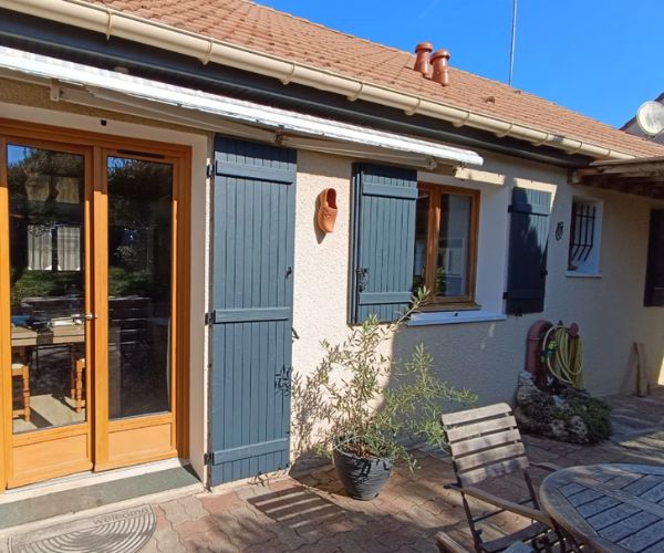 Rénovation de façade de maison avec volets repeints en bleu et menuiseries bois