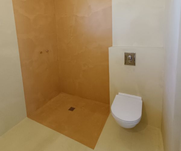 Salle de bain rénovée en béton ciré beige avec douche à l’italienne et WC suspendu à Dijon